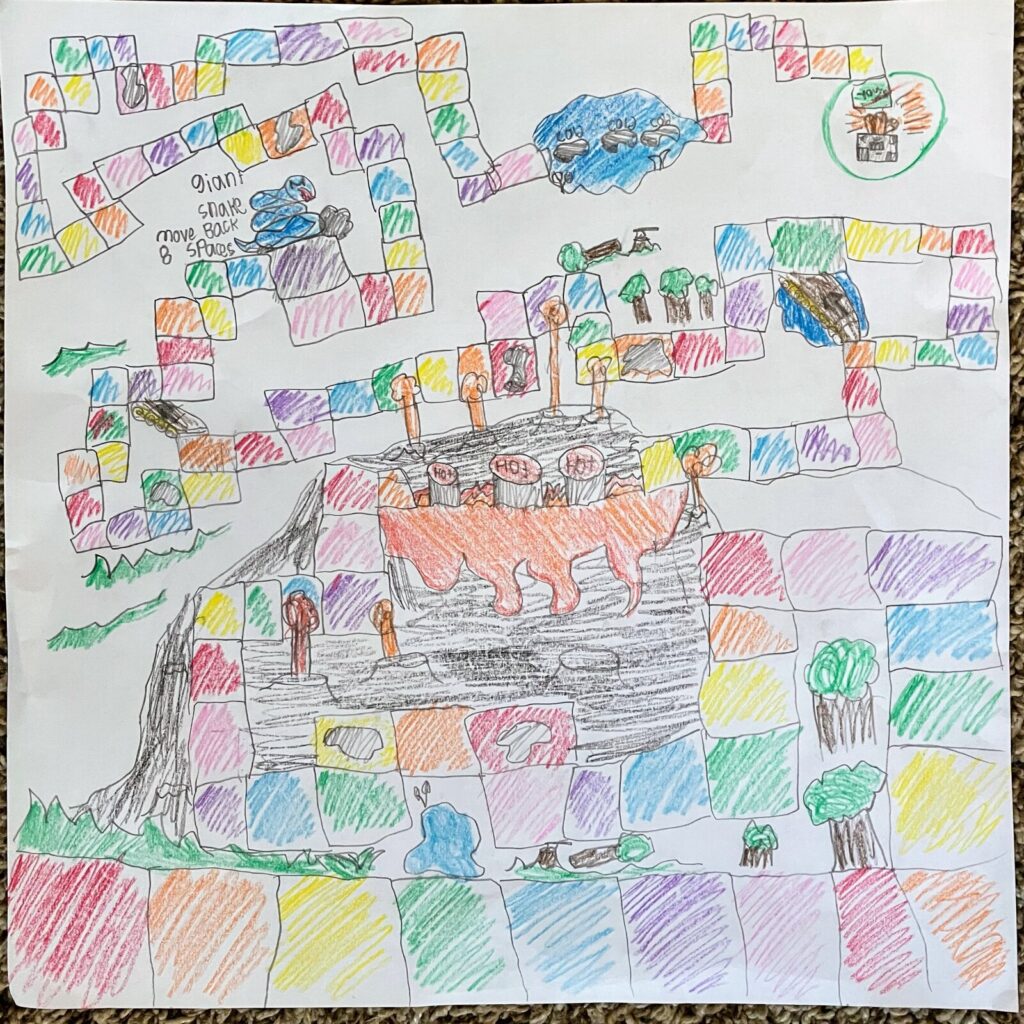Isaiah's crayon board game: a path of coloured squares winding past a volcano, a giant snake and a forest